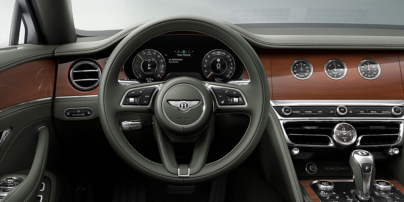 Bentley Brisbane New Bentley Flying Spur sedan front cabin in Cumbrian Green hide and Crown Cut walnut veneer showing steering wheel and Rotating Display with three clocks on face