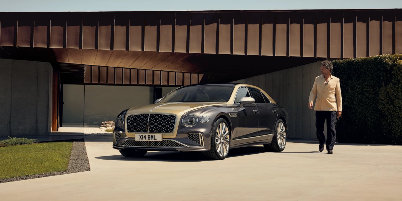 Bentley Brisbane Bentley New Flying Spur Mulliner V8 hybrid sedan front three quarters in Rose Gold over Magnetic paint, parked near modern home