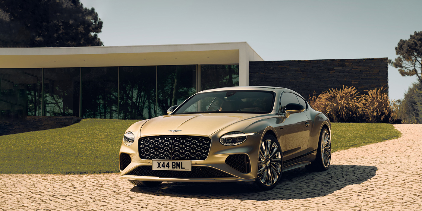 Bentley Brisbane Bentley Continental GT Mulliner coupe front three quarters in Patina paint parked outside a glass fronted building with a grass lawn behind it