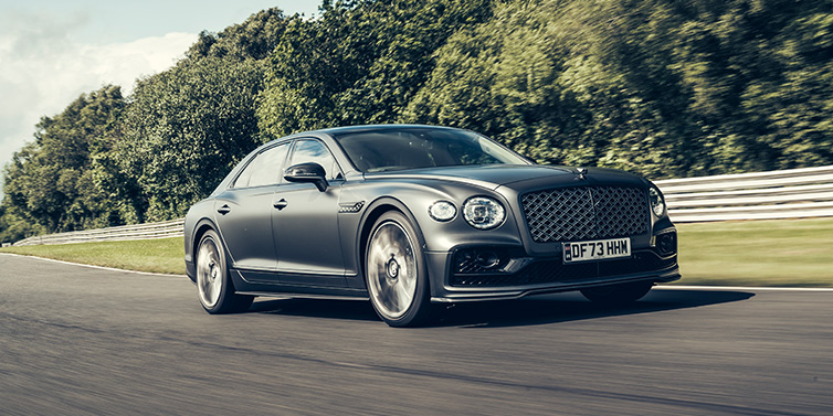 Bentley Brisbane Bentley Flying Spur Mulliner sedan front three quarter in dark grey paint driving dynamically by some trees on a track