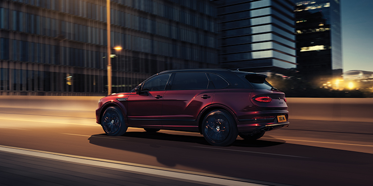 Bentley Brisbane Bentley Bentayga Extended Wheelbase Mulliner SUV in Cricket Ball red paint driving dynamically in city at night