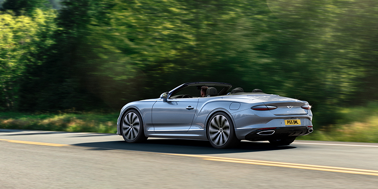 Bentley Brisbane New Bentley Continental GTC convertible side view in Silverlake paint with 22 inch ten spoke wheels driving dynamically on a country road